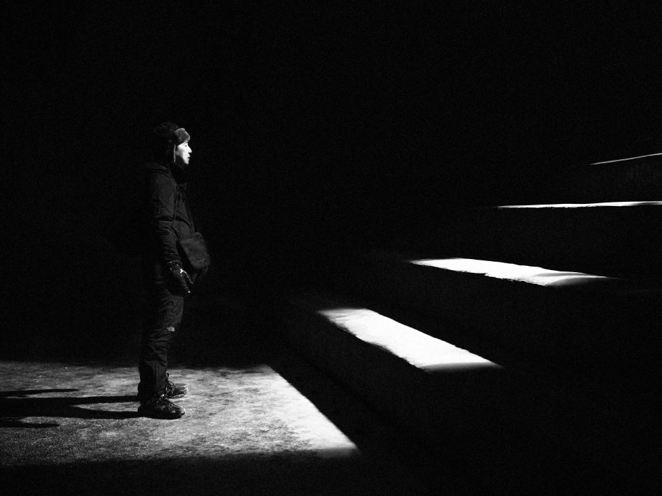 Person standing at the bottom of a set of stairs, implying progression.